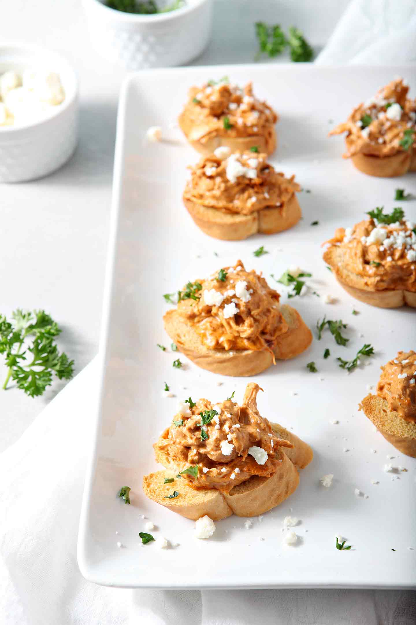 Chicken Enchilada Bruschetta lined up on a white platter before serving