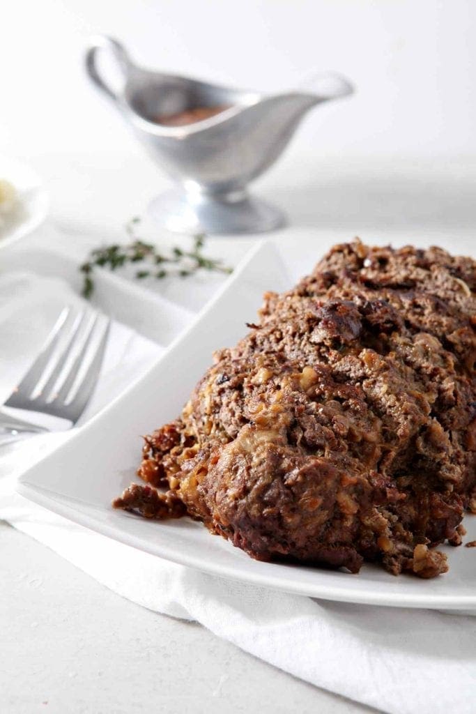 Looking for a comforting meal for the whole family? Instant Pot French Onion Meatloaf adds a flavorful kick to any dinner! | French Onion Meatloaf | Instant Pot Meatloaf | Comfort Food | Comfort Food Recipe | French Onion Flavors | French Onion | Instant Pot Dinner | Electric Pressure Cooker Recipe French Onion Meatloaf, sitting on a white platter, sliced and ready for eating