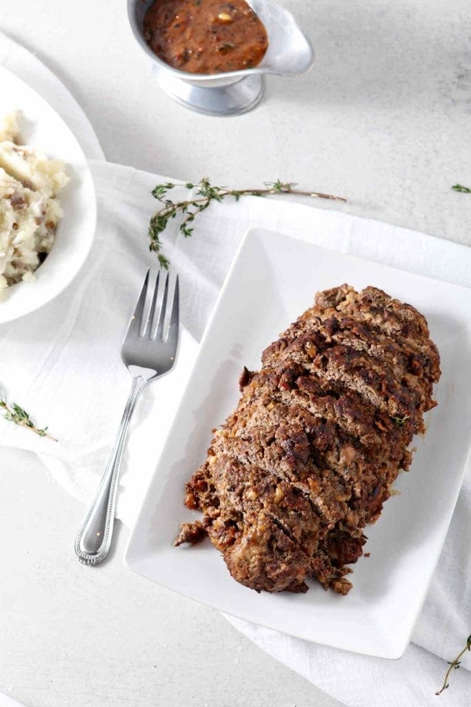 French Onion Meatloaf, sitting on a white platter, sliced and ready for eating