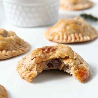 Closeup of a bitten-into Mashed Potato Beef Hand Pies with others on a white platter