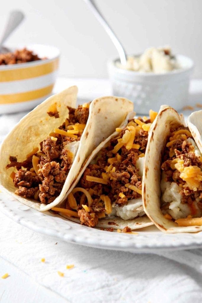 One white plate holding three Mashed Potato Chorizo Breakfast Tacos ready for eating on a white background