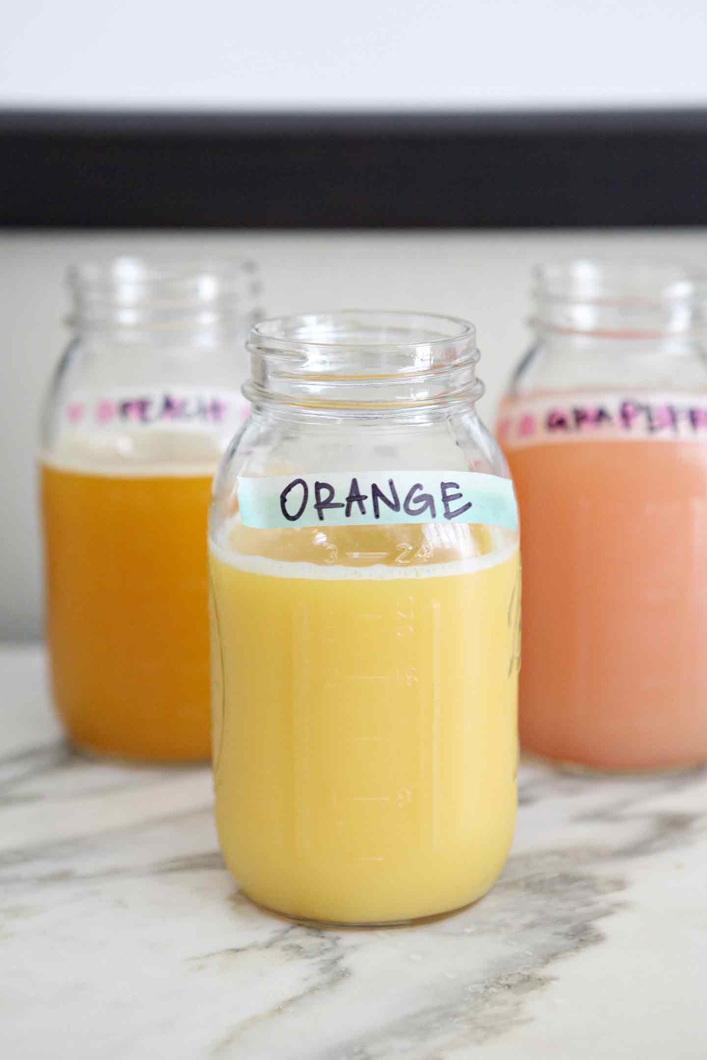 Juices, served in mason jars and labeled with washi tape, are displayed on a turquoise breakfast bar as a part of the Mimosa Bar