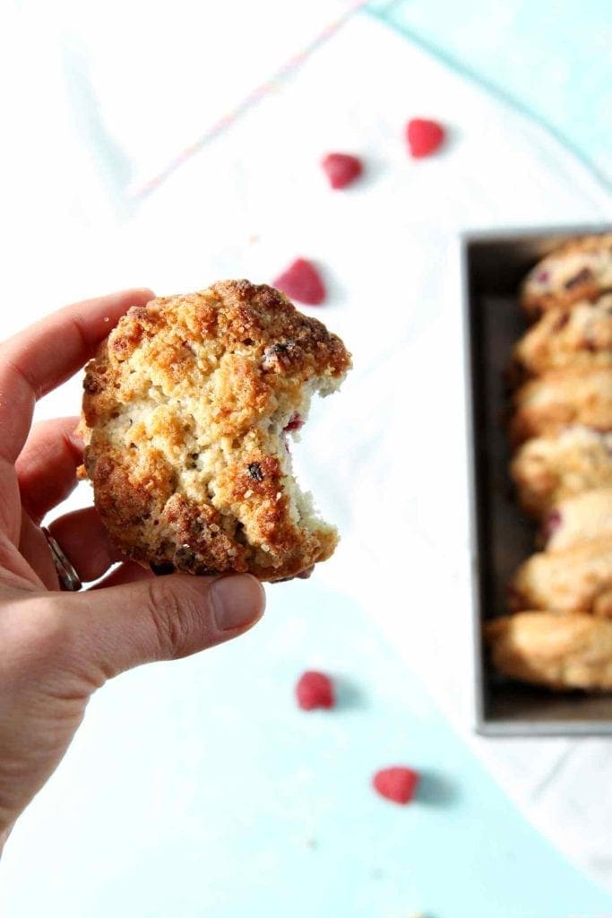 hand holding a raspberry shortcake biscuit with a bite taken