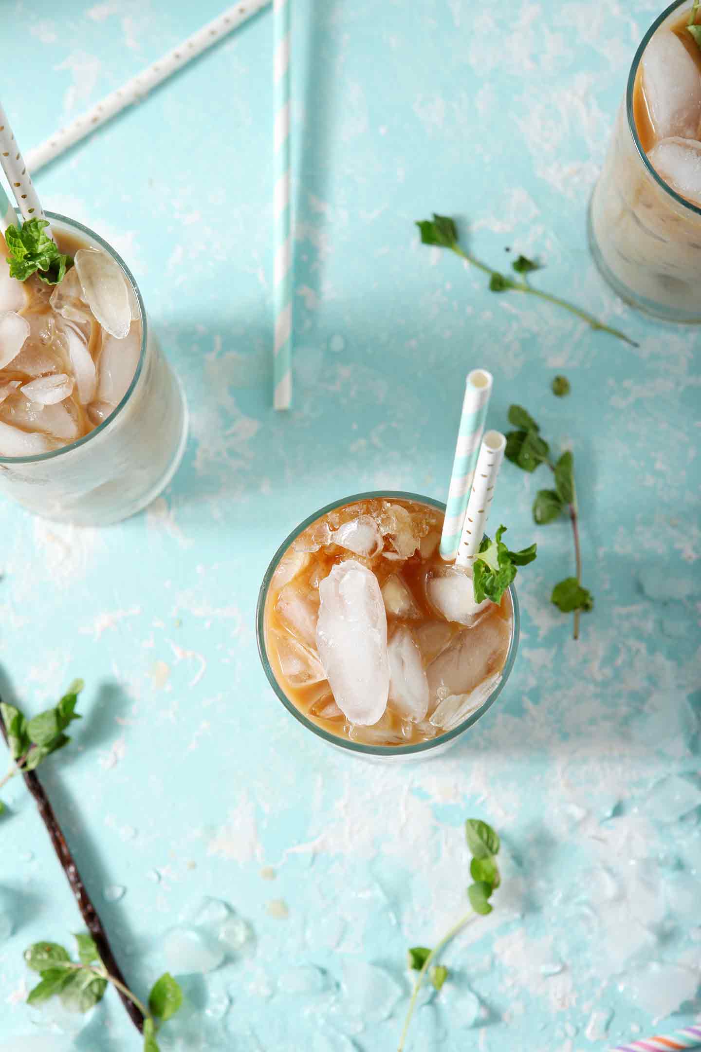 Three Dunkin' Donuts Cold Brew with Homemade Vanilla Mint Creamer, on a turquoise background, ready for drinking from above