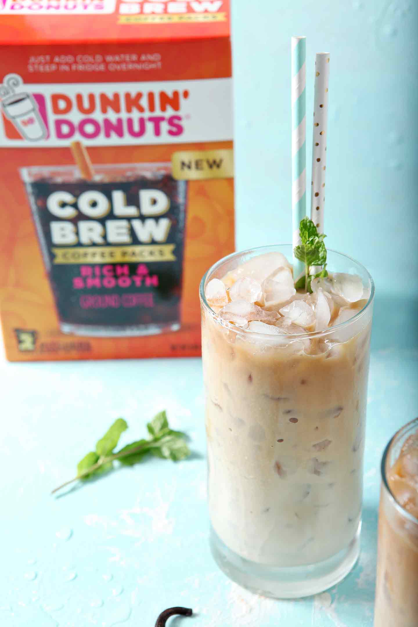 A glass of cold brew with creamer in front of a Dunkin' Donuts cold brew package