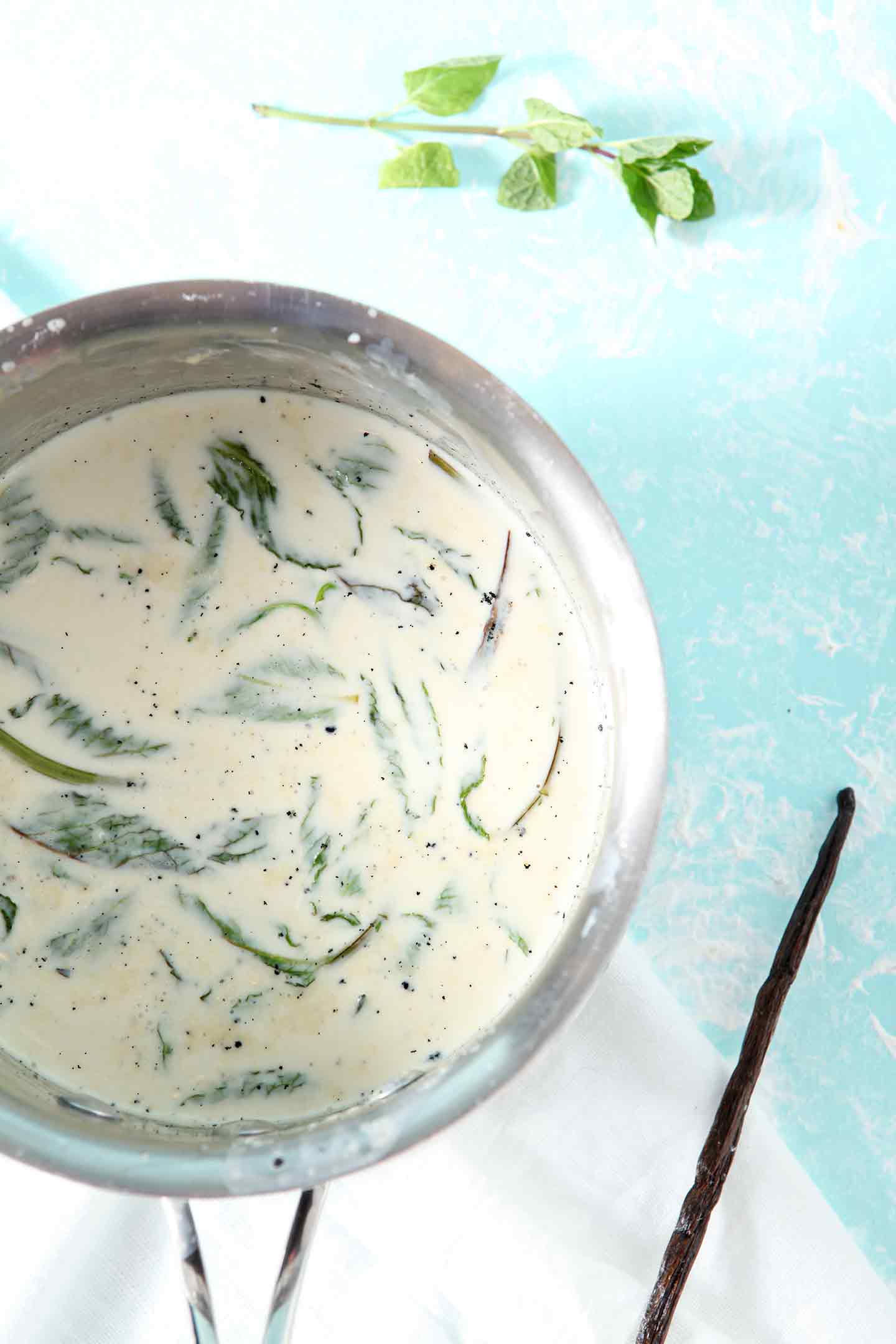 Homemade Vanilla Mint Creamer in a silver saucepan on a turquoise backdrop