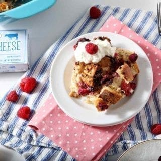 French Toast Casserole on a white plate with whipped cream and raspberries