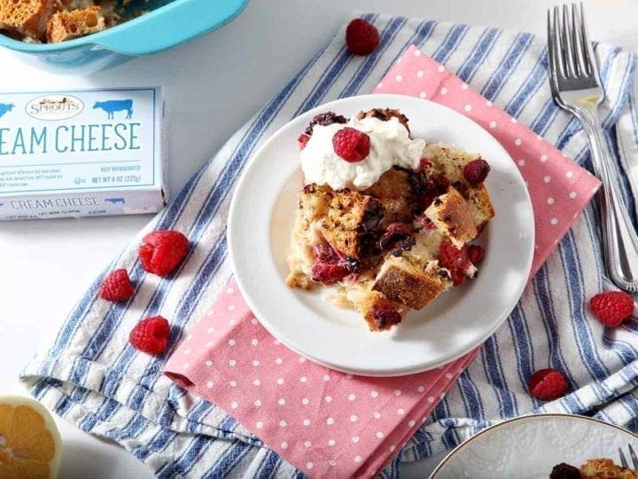 French Toast Casserole on a white plate with whipped cream and raspberries