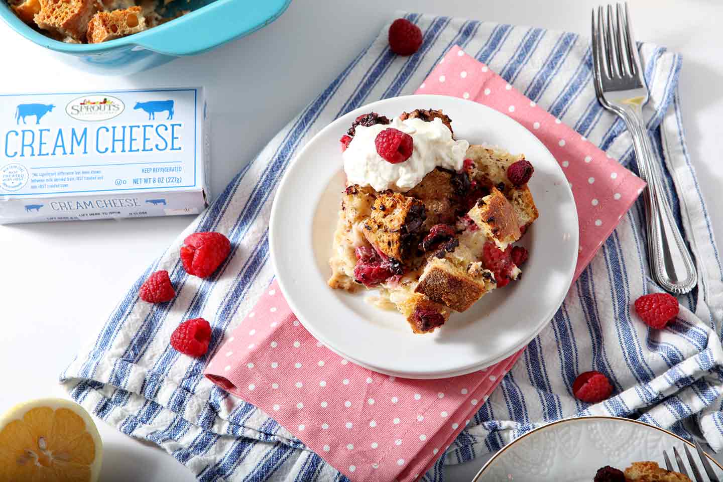 French Toast Casserole on a white plate with whipped cream and raspberries