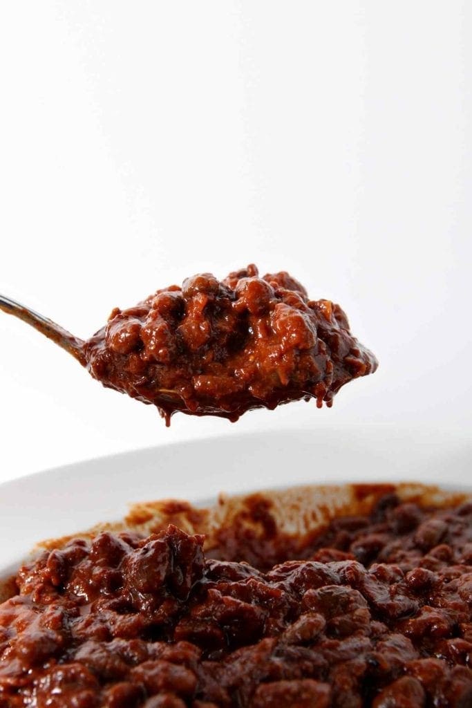 A spoon holds a scoop of Instant Pot Baked Beans