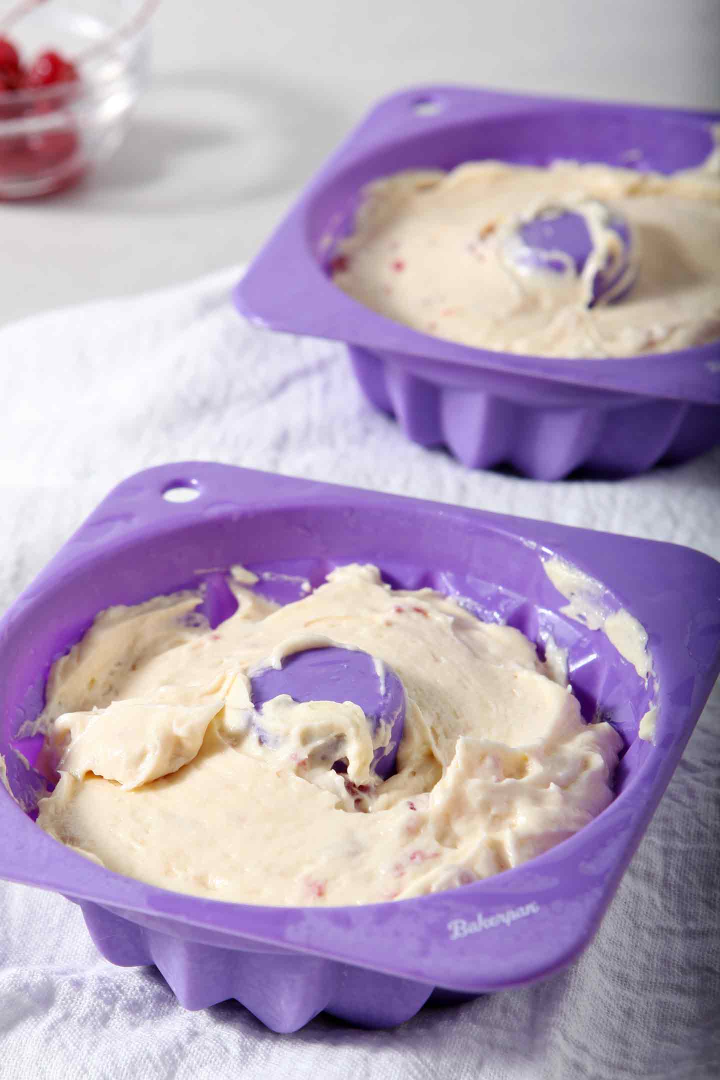 Mini White Chocolate-Cherry Bundt Cakes (Instant Pot Cake) batter sits in purple mini Bundt cake pans before baking