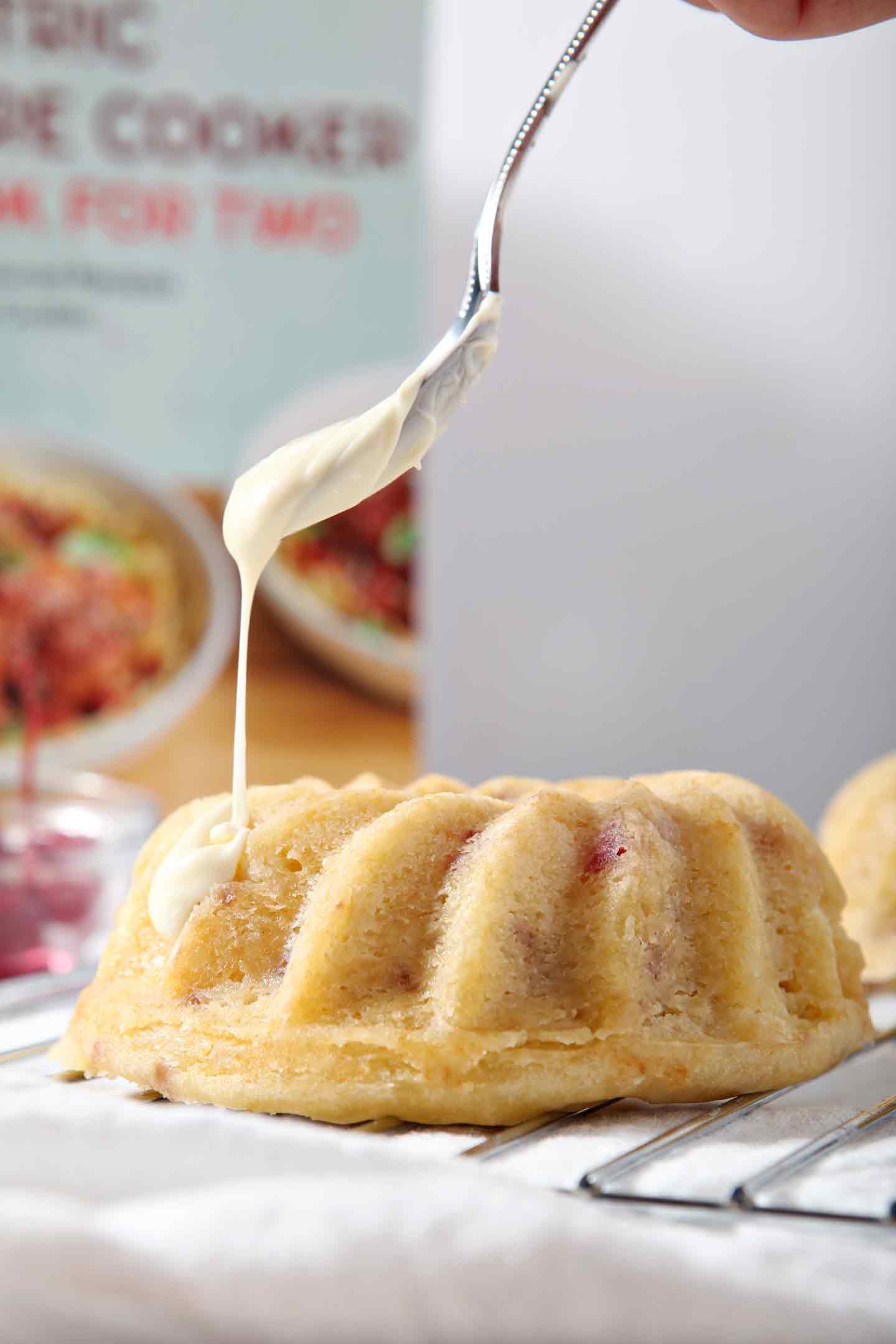 White chocolate is drizzled onto a baked Mini White Chocolate-Cherry Bundt Cake (Instant Pot Cake).