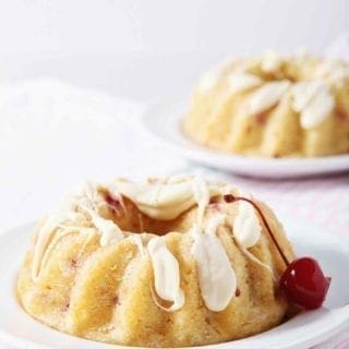 white chocolate bundt cake on a white plate with a cherry