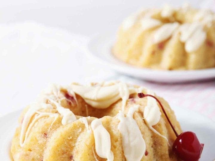 white chocolate bundt cake on a white plate with a cherry
