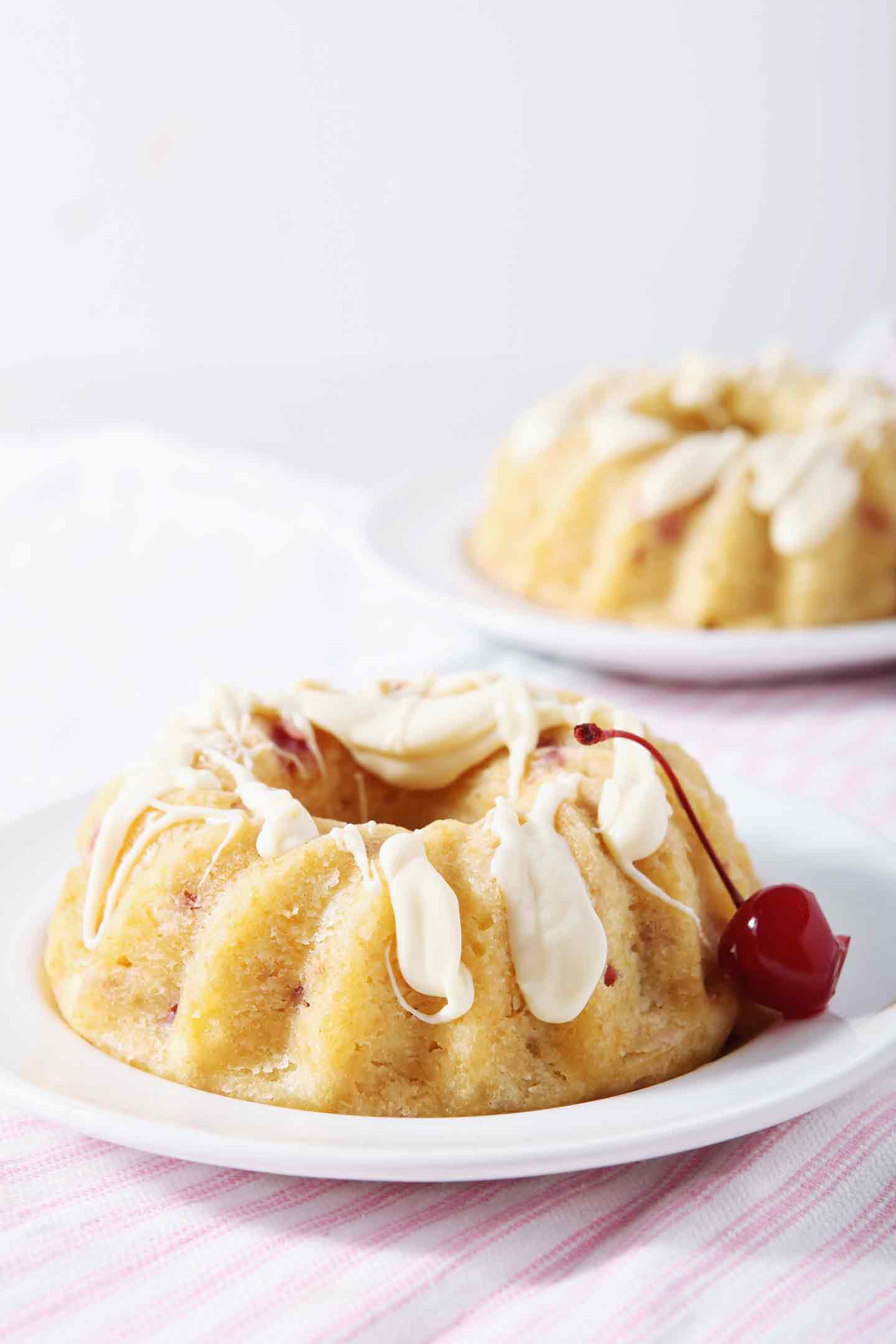 white chocolate bundt cake on a white plate with a cherry