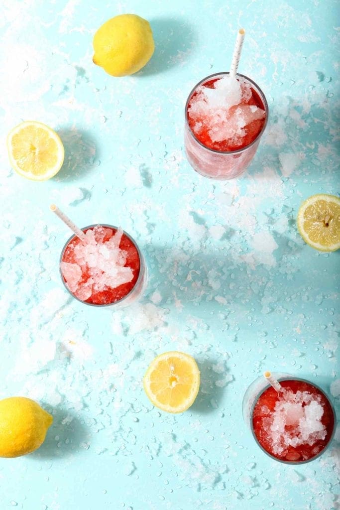 Three glasses of Arnold Palmer Iced Tea Lemonade Mocktail are surrounded by ice and lemon slices before enjoying