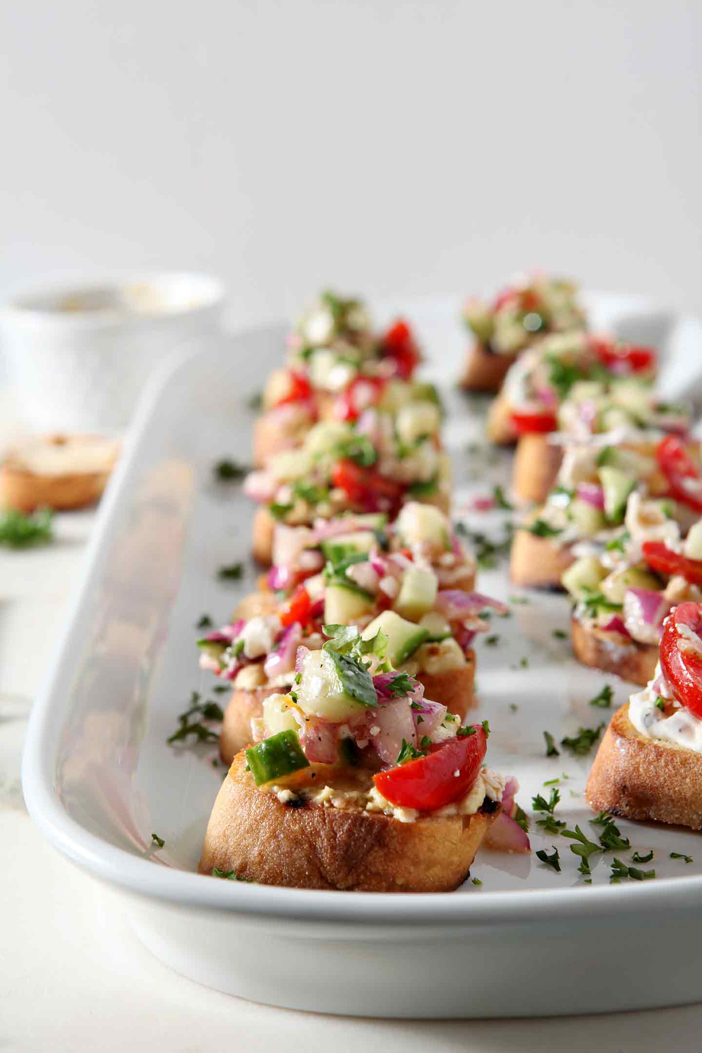 Greek Bruschetta sit on a white platter at a party before serving