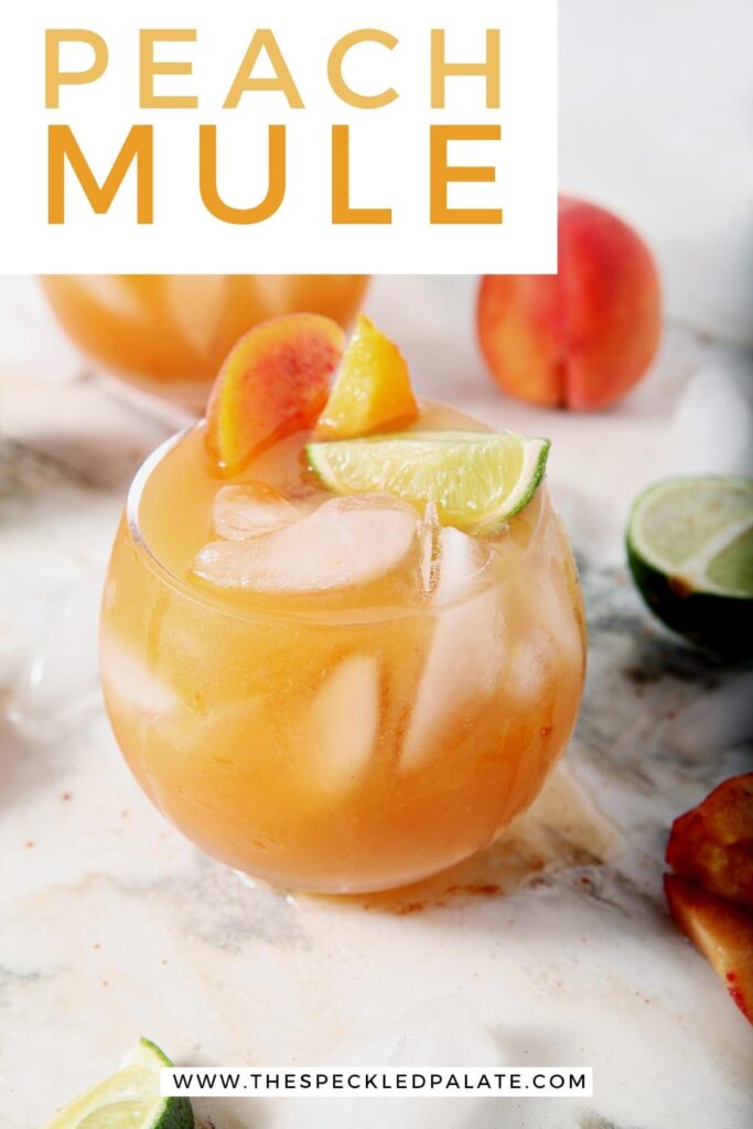 Two Peach Moscow Mules, garnished with limes and peaches, sit on a marble surface, with Pinterest text