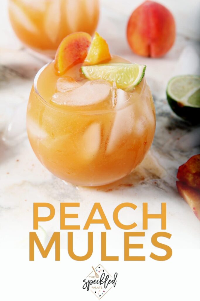 Two Peach Moscow Mules, garnished with limes and peaches, sit on a marble surface, with Pinterest text