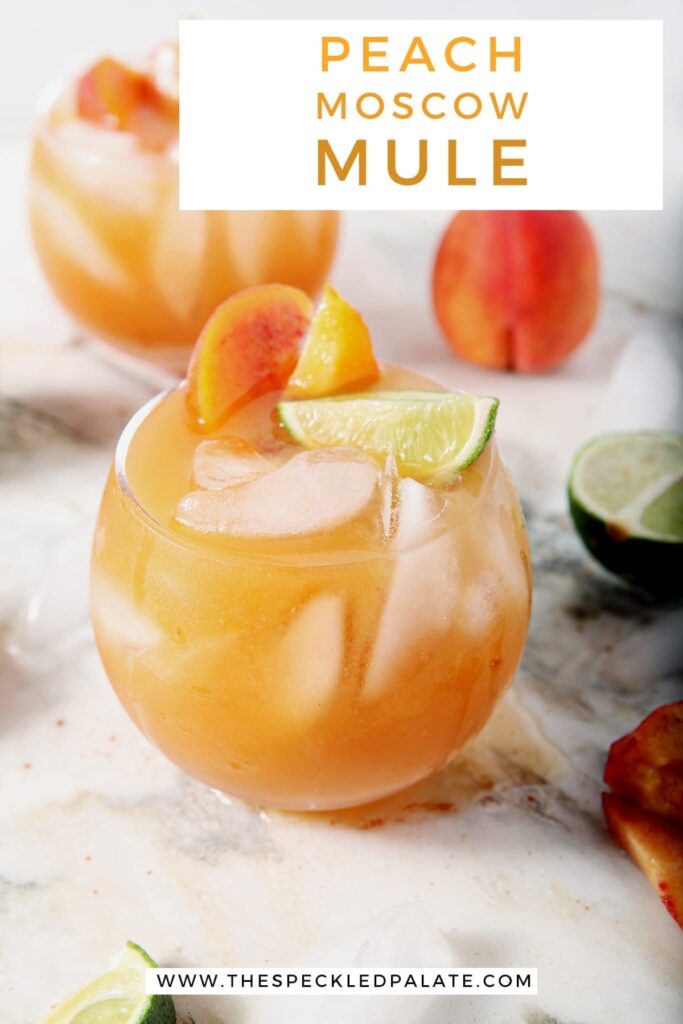 Two Peach Moscow Mules, garnished with limes and peaches, sit on a marble surface, with Pinterest text