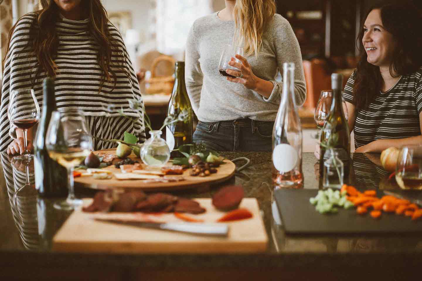 Three women spend time together near a spread of food