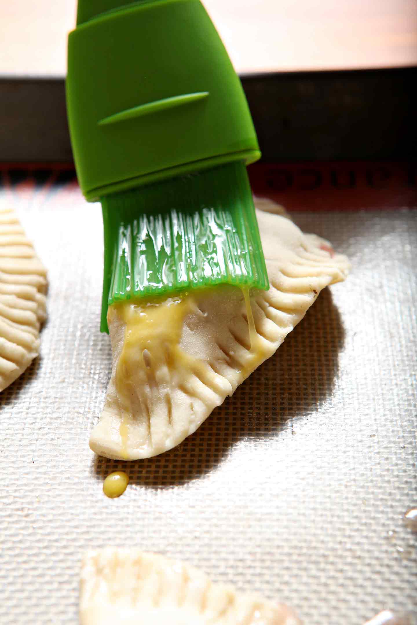 Egg wash is brushed onto Blackberry Peach Hand Pies before they bake