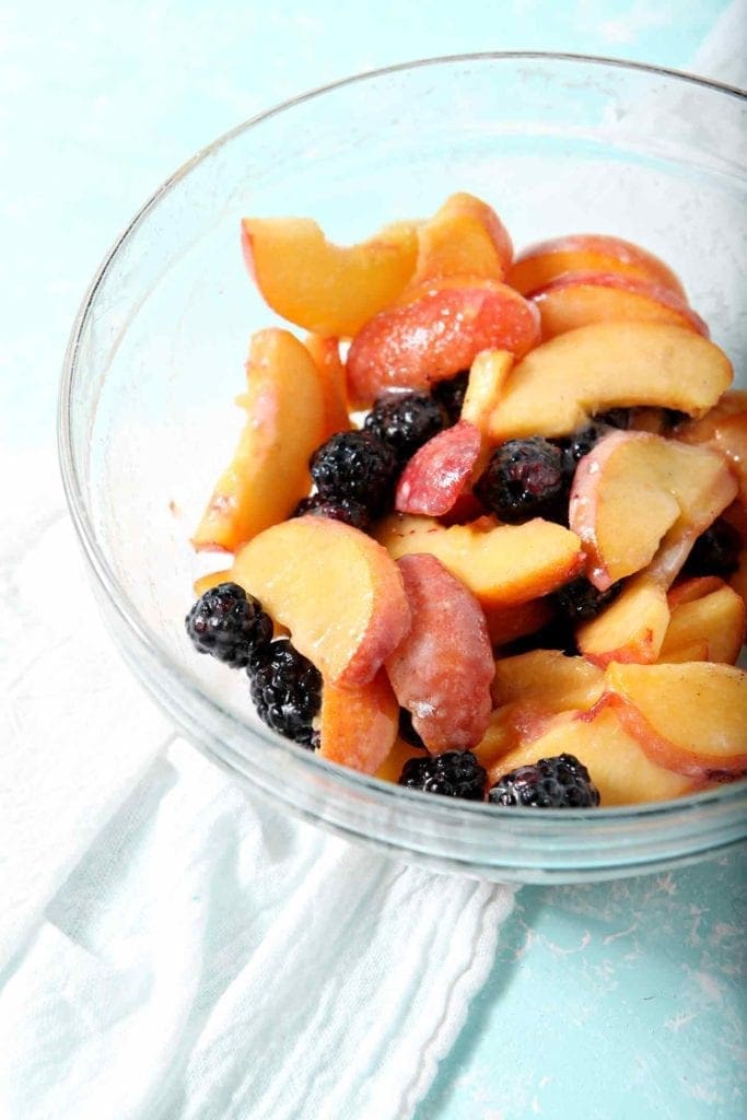 Sweetened blackberries and peach slices in a bowl