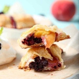 A Blackberry Peach Hand Pie is shown on a plate, halved, with Bourbon Whipped Cream