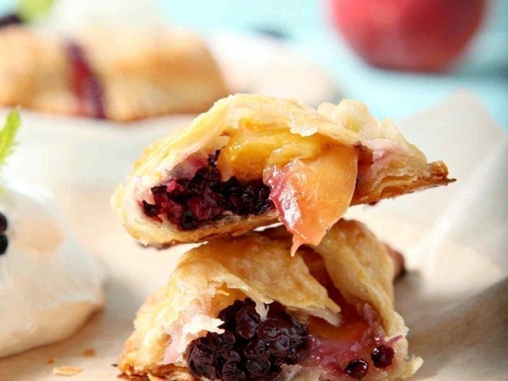 A Blackberry Peach Hand Pie is shown on a plate, halved, with Bourbon Whipped Cream