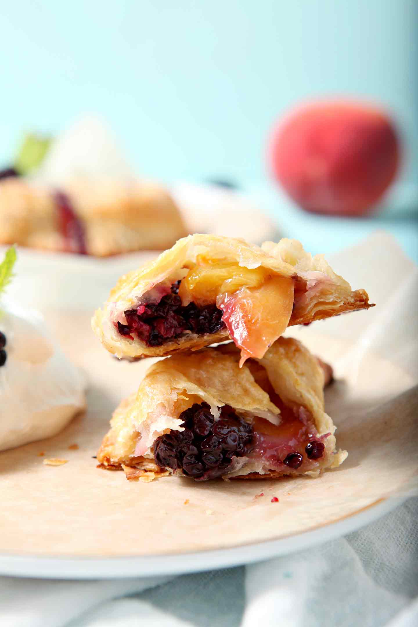 A Blackberry Peach Hand Pie is shown on a plate, halved, with Bourbon Whipped Cream