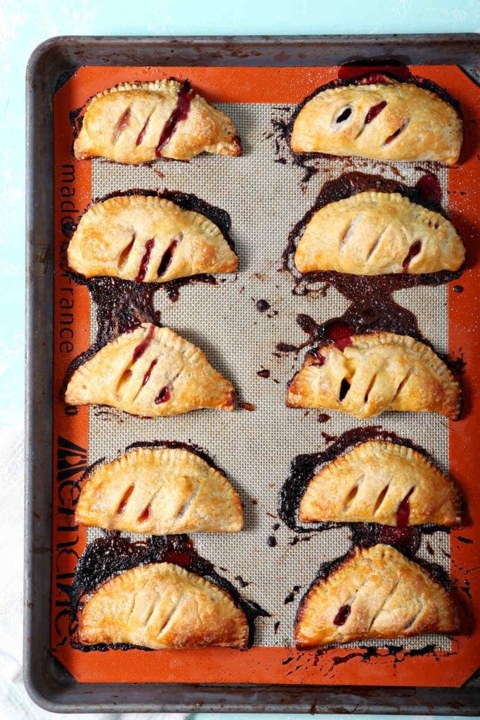 Baked Blackberry Peach Hand Pies sit on a baking sheet, straight out of the oven