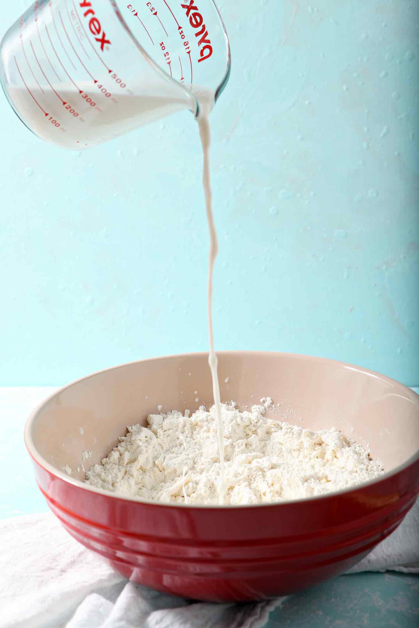 Milk and apple cider vinegar are poured into the dry ingredients for the crust for Blackberry Peach Hand Pies