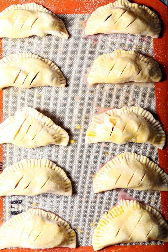 Blackberry Peach Hand Pies line a baking sheet before baking