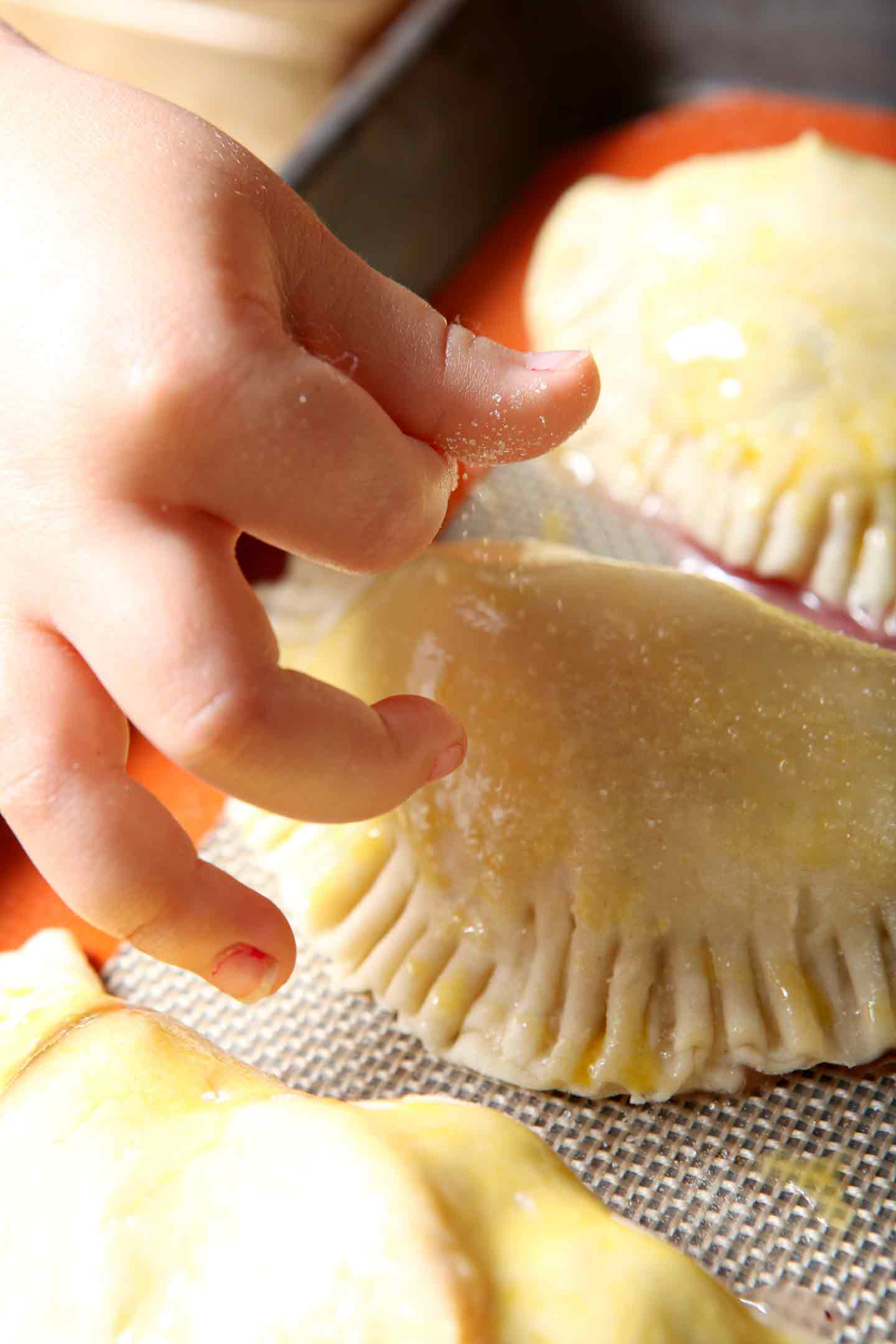 Sugar is sprinkled onto a Blackberry Peach Hand Pie before it bakes