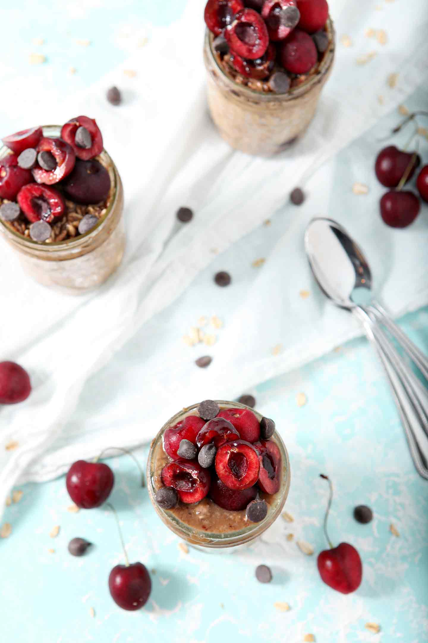 Overhead image of Cherry Overnight Oats with two silver spoons and cherries