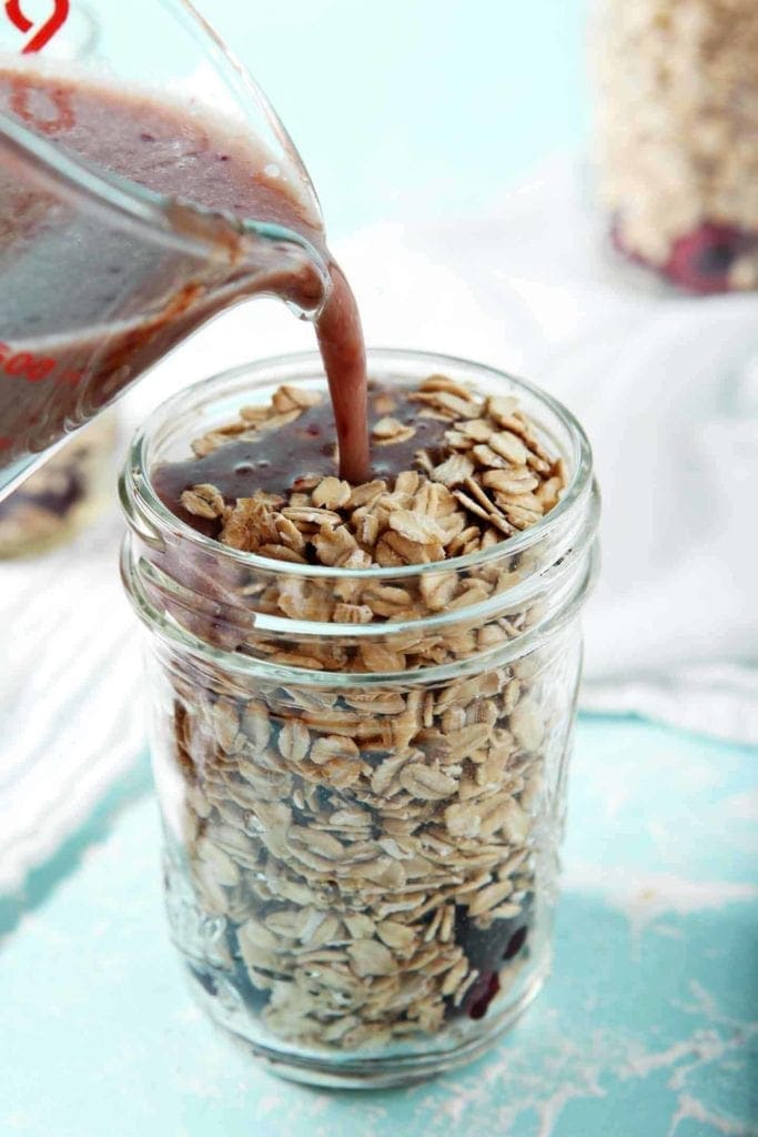 A mixture of cashew milk, maple syrup and cherry puree are poured in top of rolled oats to make overnight oats