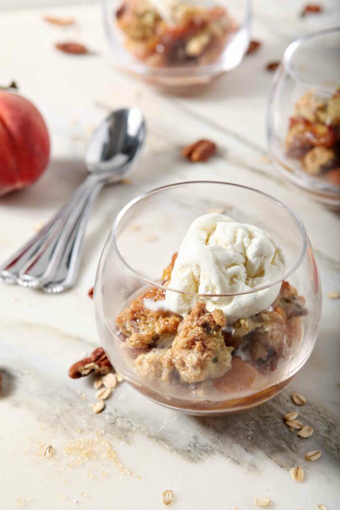 Dairy free ice cream melts on top of a serving of Dairy Free Peach Cobbler