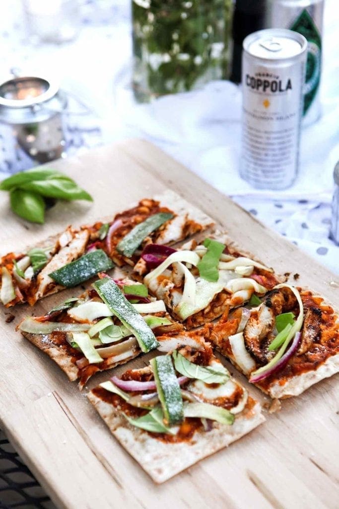 A Grilled BBQ Chicken Flatbread sits on an outdoor table at an outdoor gathering