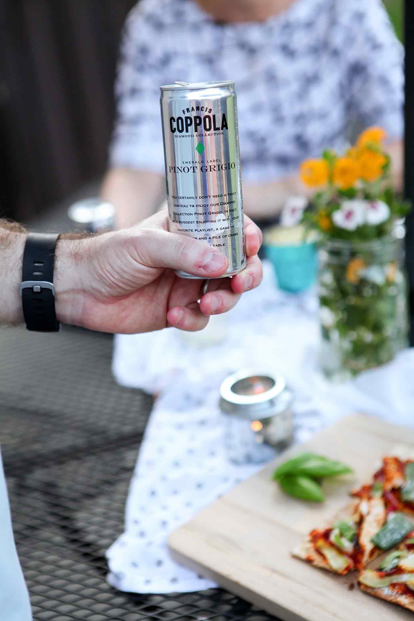 A man holds a Coppola Diamond Collection can at an outdoor gathering