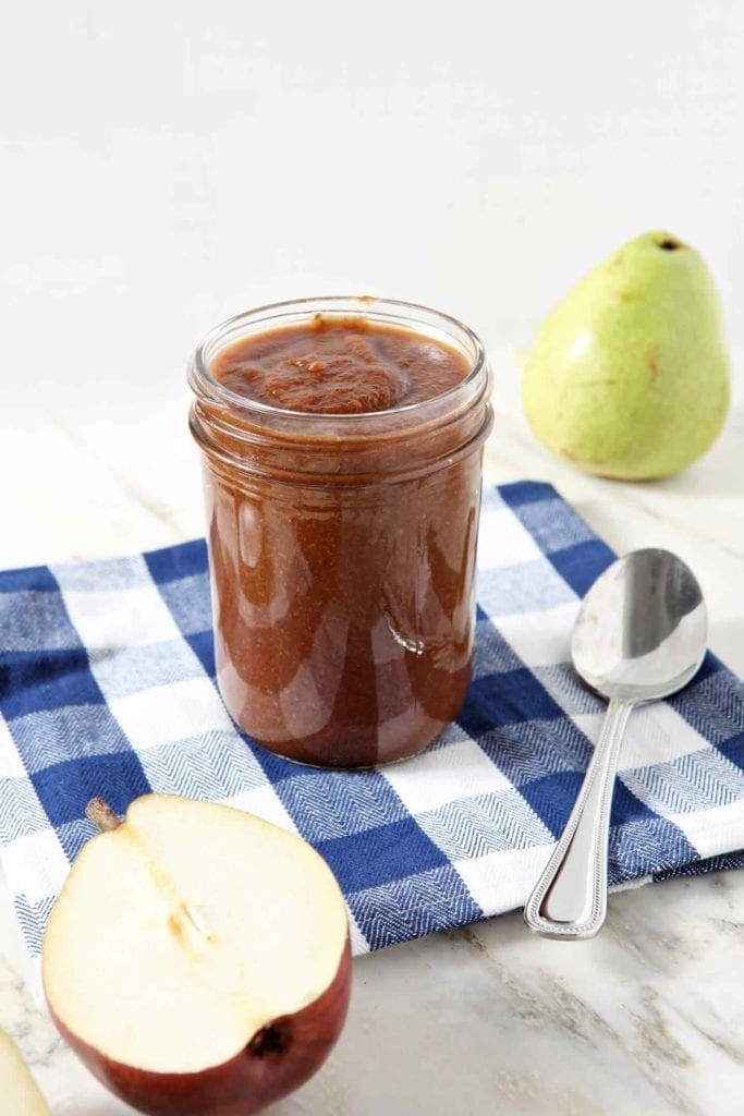 A jar of Pear BBQ Sauce sits on a blue-and-white checkered napkin