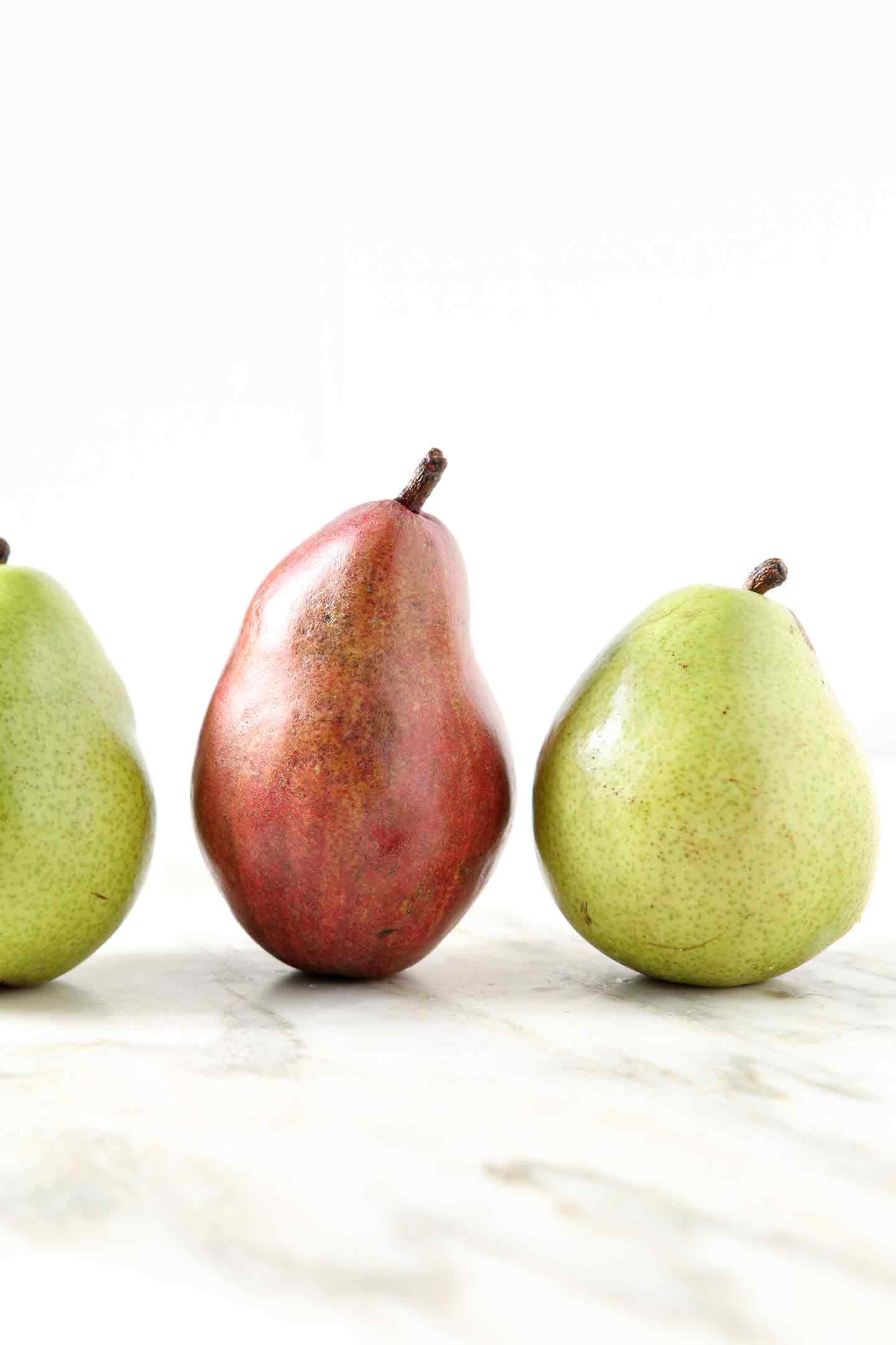 Three pears are lined up on a marble background