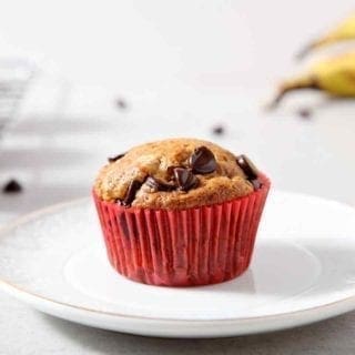 A lone Vegan Banana Chocolate Chip Muffin is placed on a white plate for serving