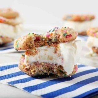 A bitten-into Funfetti Ice Cream Sandwich sits on a blue striped napkin, surrounded by other ice cream sandwiches