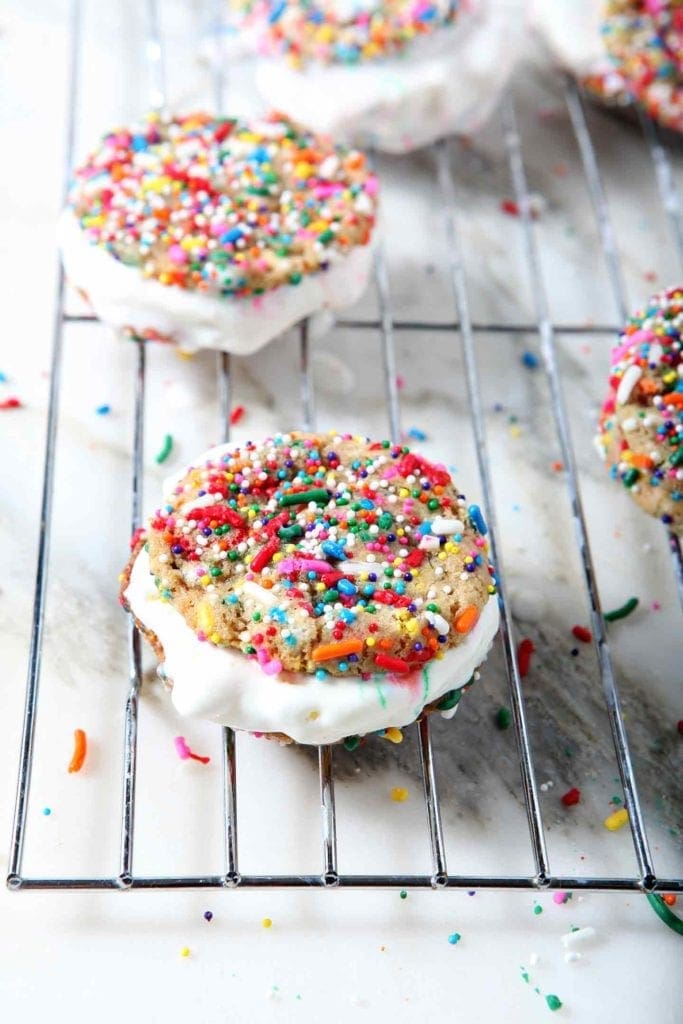 Several Funfetti Ice Cream Sandwiches sit on a wire cooling rack before going into the freezer