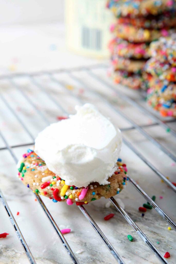 A scoop of ice cream is placed on top of a Funfetti Cookie 