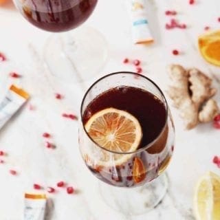 Two Pomegranate Ginger Orange Sparkling Mocktails, garnished with lemon slices