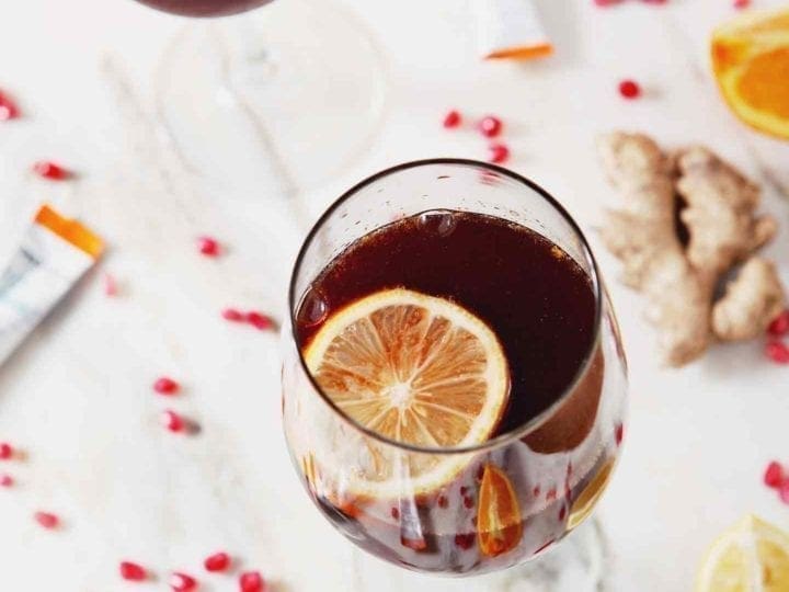 Two Pomegranate Ginger Orange Sparkling Mocktails, garnished with lemon slices