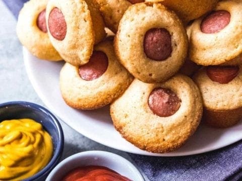 Corn Dog Mini Muffins are served on a plate with ketchup and mustard for dipping