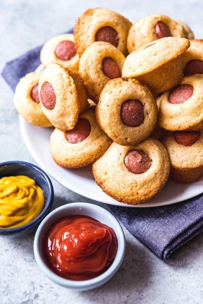 Corn Dog Mini Muffins are served on a plate with ketchup and mustard for dipping