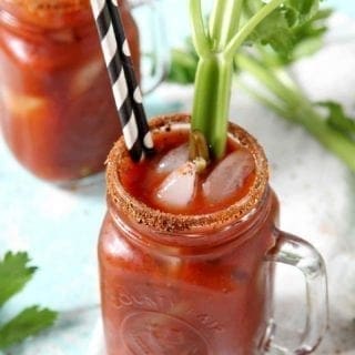 Two BBQ Bloody Marys are garnished with pickled green beans and fresh celery sticks